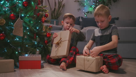 children-received-gifts-from-the-santa-and-shake-and-listen-to-what-is-inside-the-box-sitting-under-the-Christmas-tree.-High-quality-4k-footage